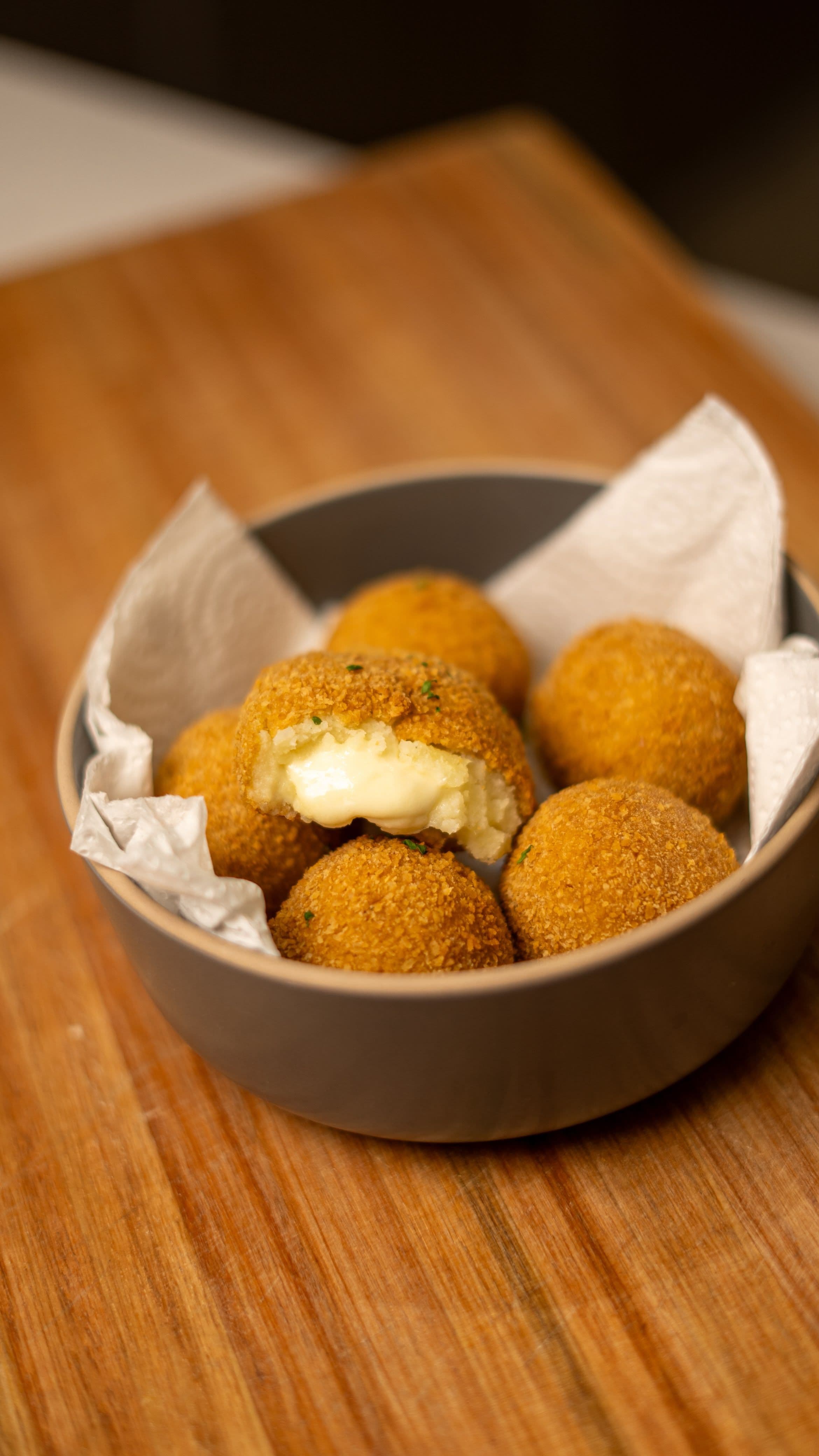 Croquetas doradas en un bowl, una partida al medio con el relleno cremoso a la vista.